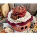 The custom made hat the gourd character is wearing is dark red with white lace trim. Embellishments include real acorns and cedar rosettes.